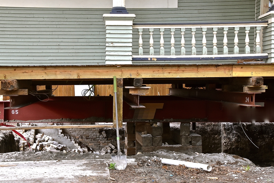An old house rests on steel girders as a new concrete 
basement and foundation is being created